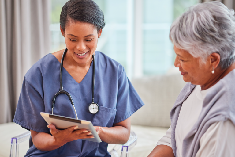 A healthcare professional shows a tablet to an elderly patient, both smiling with RestAssure.
